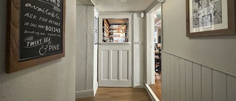 Un pasillo con un letrero que indica disponibilidad de suites, un área de bar visible a través de una puerta y un cuadro en la pared.
