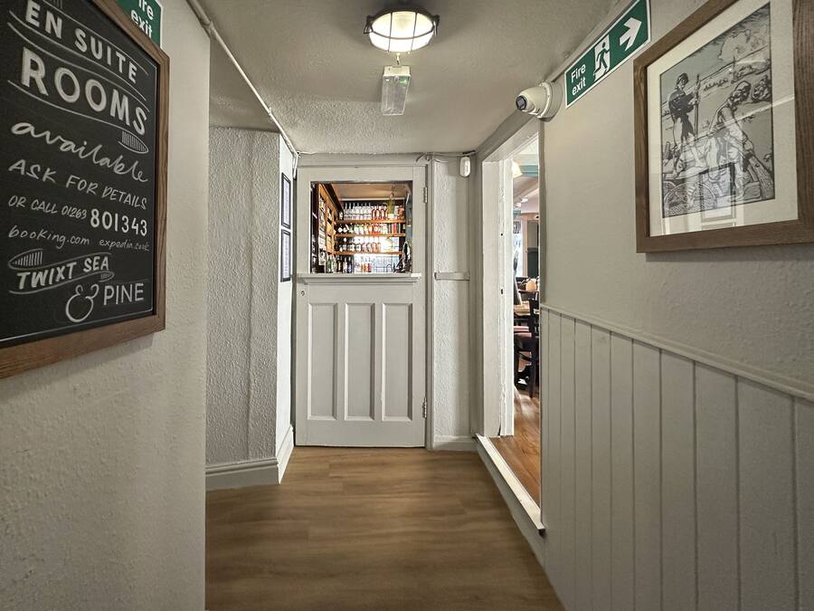 A hallway with a sign indicating suite rooms are available, a bar area visible through a doorway, and a framed picture on the wall.