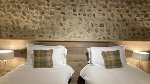 A double bed with white linens and plaid pillows, set against a stone wall. - The Lobster  (Sheringham)