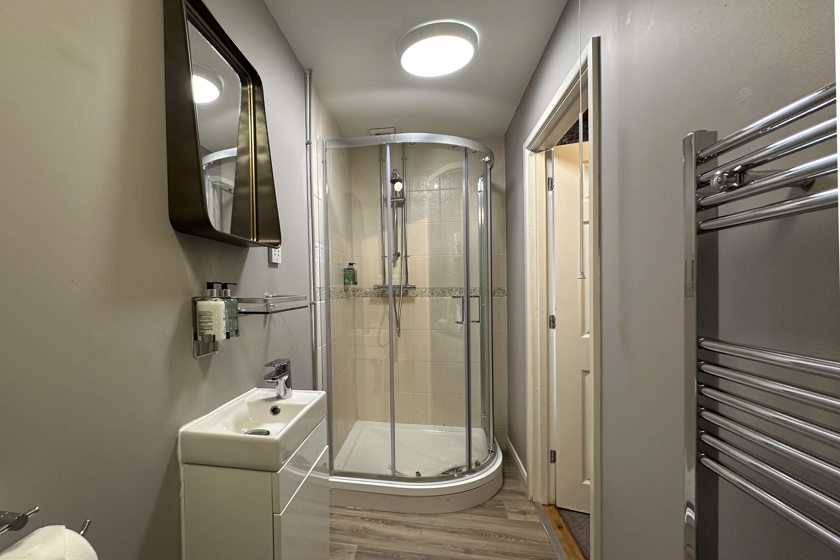A modern bathroom with a glass-enclosed shower, a sink, and a mirror.