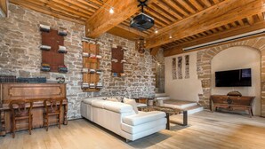 A cozy living room with a stone wall, wooden ceiling beams, a white sofa, a coffee table, and a television. - Appartement de Standing au Cœur du Vieux Lyon (Lyon)
