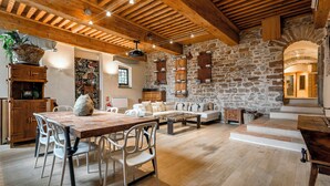 A rustic interior with exposed wooden beams, stone walls, a dining area with a table and chairs, and a cozy seating area. - Appartement de Standing au Cœur du Vieux Lyon (Lyon)