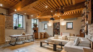 A spacious living area with a wooden ceiling, a white sofa, a dining table with chairs, and a coffee table. - Appartement de Standing au Cœur du Vieux Lyon (Lyon)