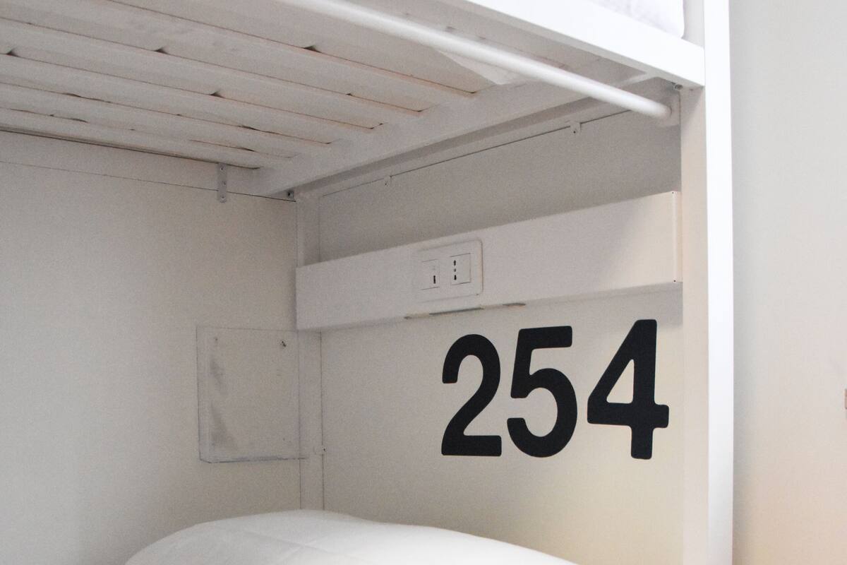 A bunk bed with a number '254' on the wall and drawer.
