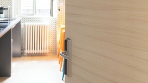 Una cocina con una puerta identificada con la palabra KITCHEN y una ventana al fondo.