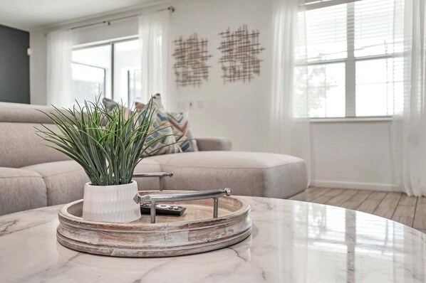 A modern living room with a marble coffee table, a potted plant, and a minimalist decor.