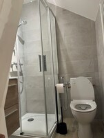 Un baño moderno con ducha de vidrio, inodoro y lavamanos.