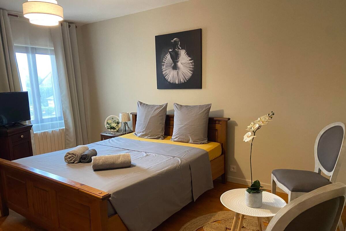 A neatly arranged bedroom with a bed, bedside table, lamp, and a television.