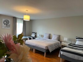 Habitación de hotel con dos camas, una mesita de noche con lámpara, luz de techo y ventana con cortinas.
