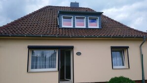 A house with a tiled roof, a front door, and a small porch. - Gästehaus Barbara mit Garage in 26919 Brake (Brake (Unterweser))