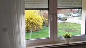 A room with a window overlooking a garden and parked cars. - Gästehaus Barbara mit Garage in 26919 Brake (Brake (Unterweser))