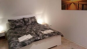 A bedroom with a bed, a nightstand, and a painting on the wall. - Gästehaus Barbara mit Garage in 26919 Brake (Brake (Unterweser))