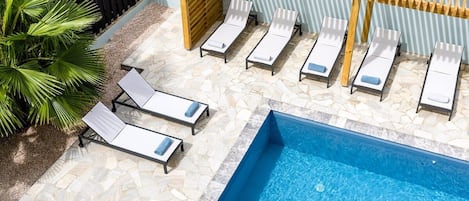 Et poolområde med liggestole og en træpergola.