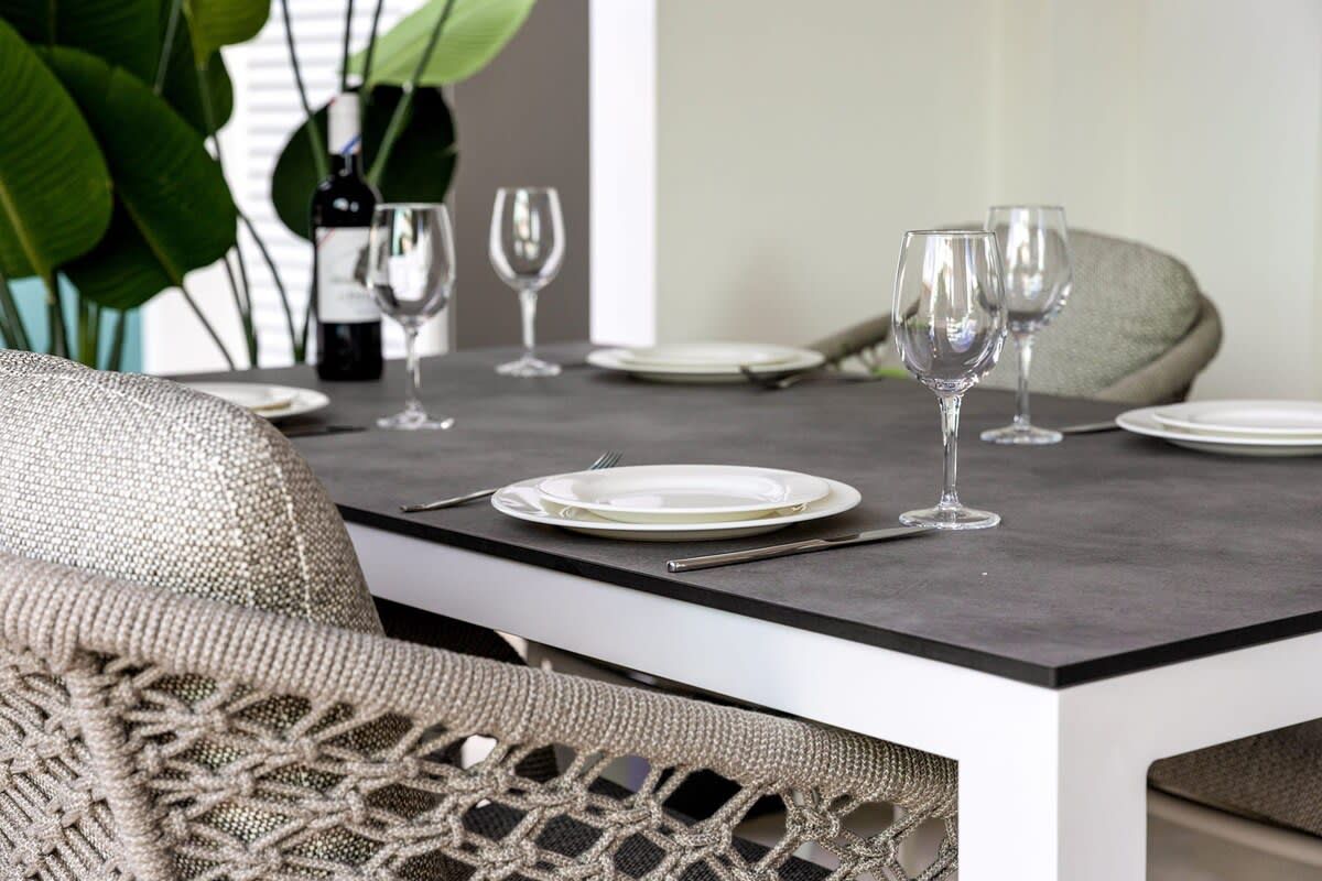 A dining table with plates, cutlery, and wine glasses set for four.