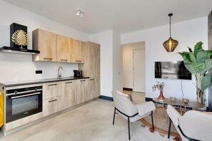 Une cuisine moderne avec des meubles en bois, un four encastré et un coin repas comprenant une table ronde et des chaises.