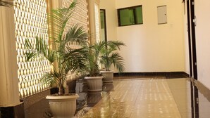 Un couloir doté d’un sol brillant, de plantes en pot et d’un mur décoratif.
