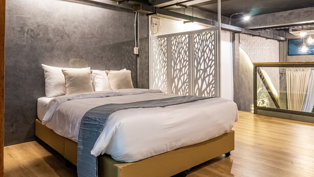 A modern bedroom with a large bed, wooden flooring, and a decorative partition. - Usman Halal Home (Bangkok)