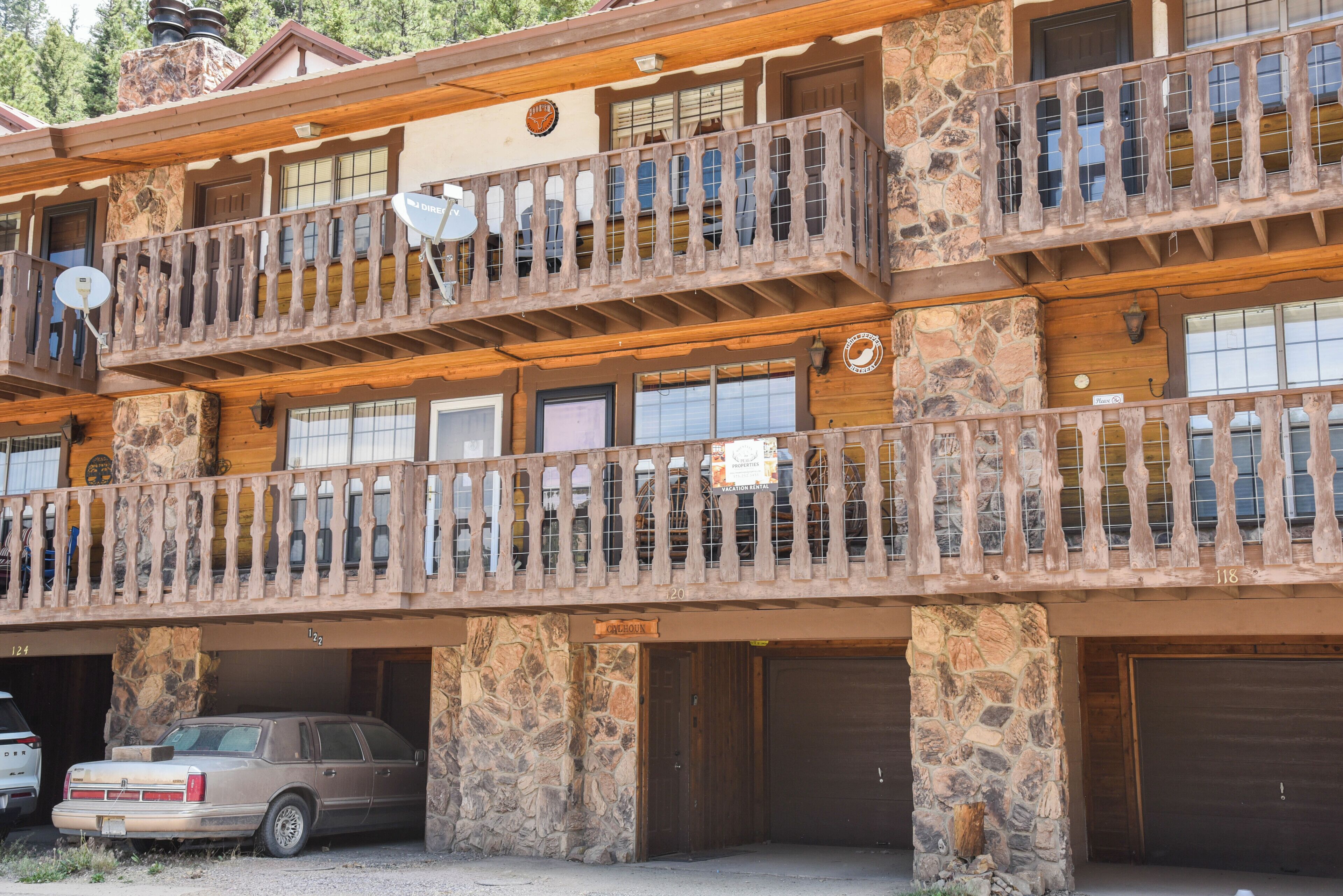 A multi-story building with balconies, stone walls, and a garage area.