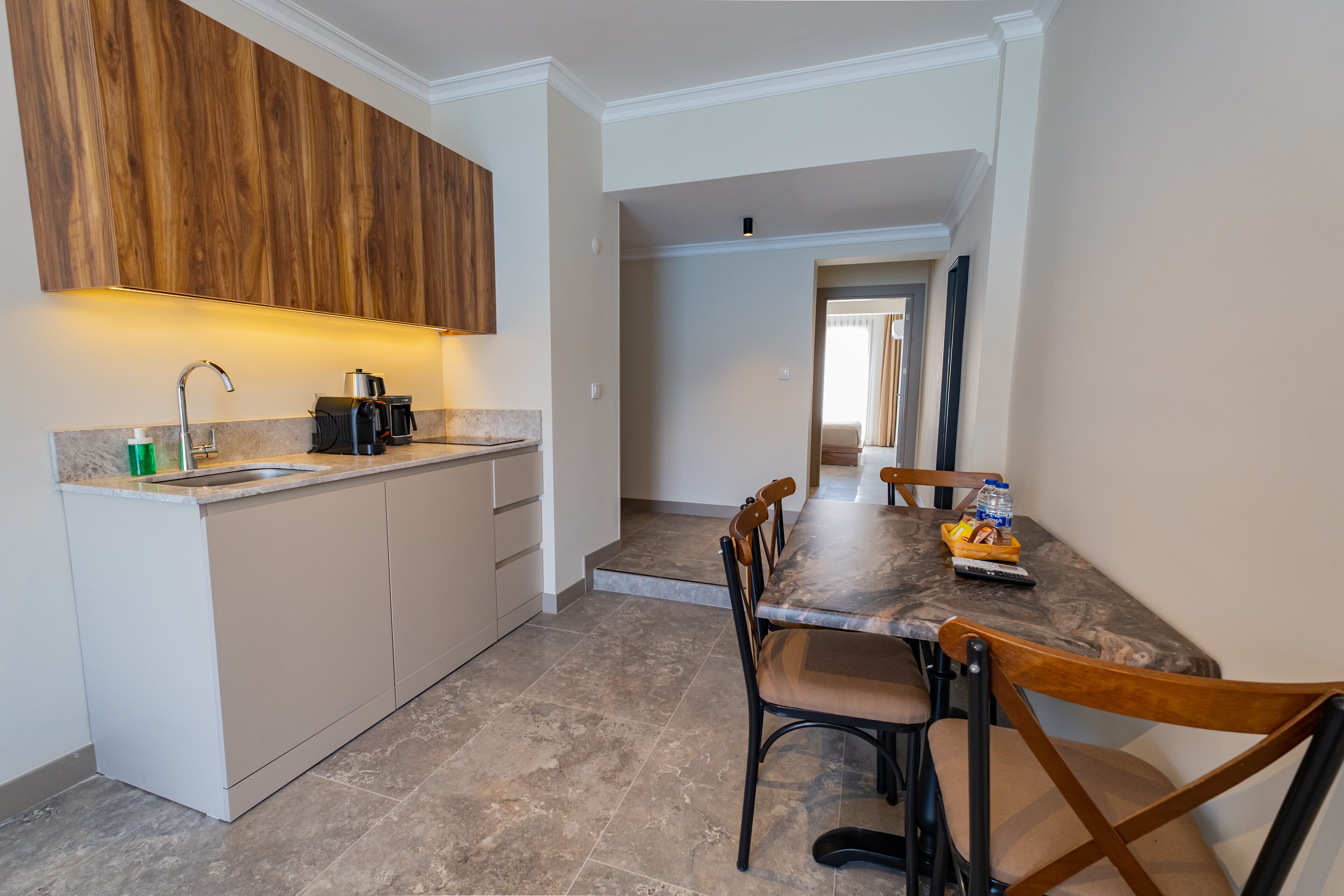 A modern kitchen with a built-in stove, a sink, and wooden cabinets. There is a dining table with chairs and a water bottle on it.