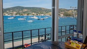 A balcony with a view of a marina, boats, and a hilly landscape.