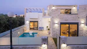 A modern villa with a swimming pool, stone walls, and outdoor seating areas. - Villa Megalith (Chania)
