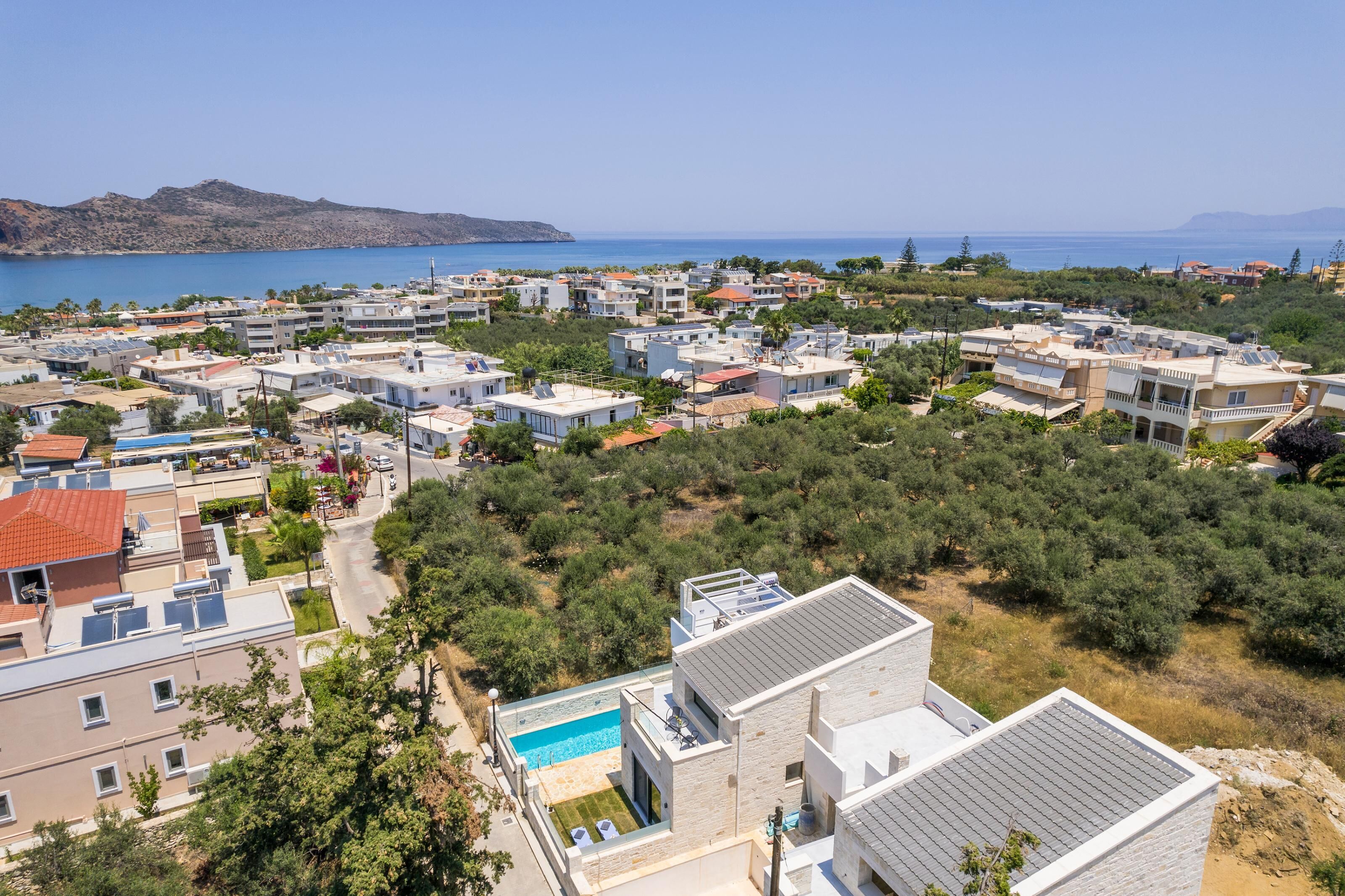 Un quartier résidentiel en bord de mer, avec des maisons modernes, une piscine et une vue sur la mer.