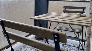 Une terrasse sur le toit, dotée de tables et de bancs en bois, qui offre une vue sur le paysage urbain, avec ses bâtiments et son ciel dégagé.