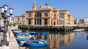 Un bâtiment situé au bord de l’eau, doté d’un grand dôme et de deux minarets, et entouré d’un canal où plusieurs bateaux sont amarrés.