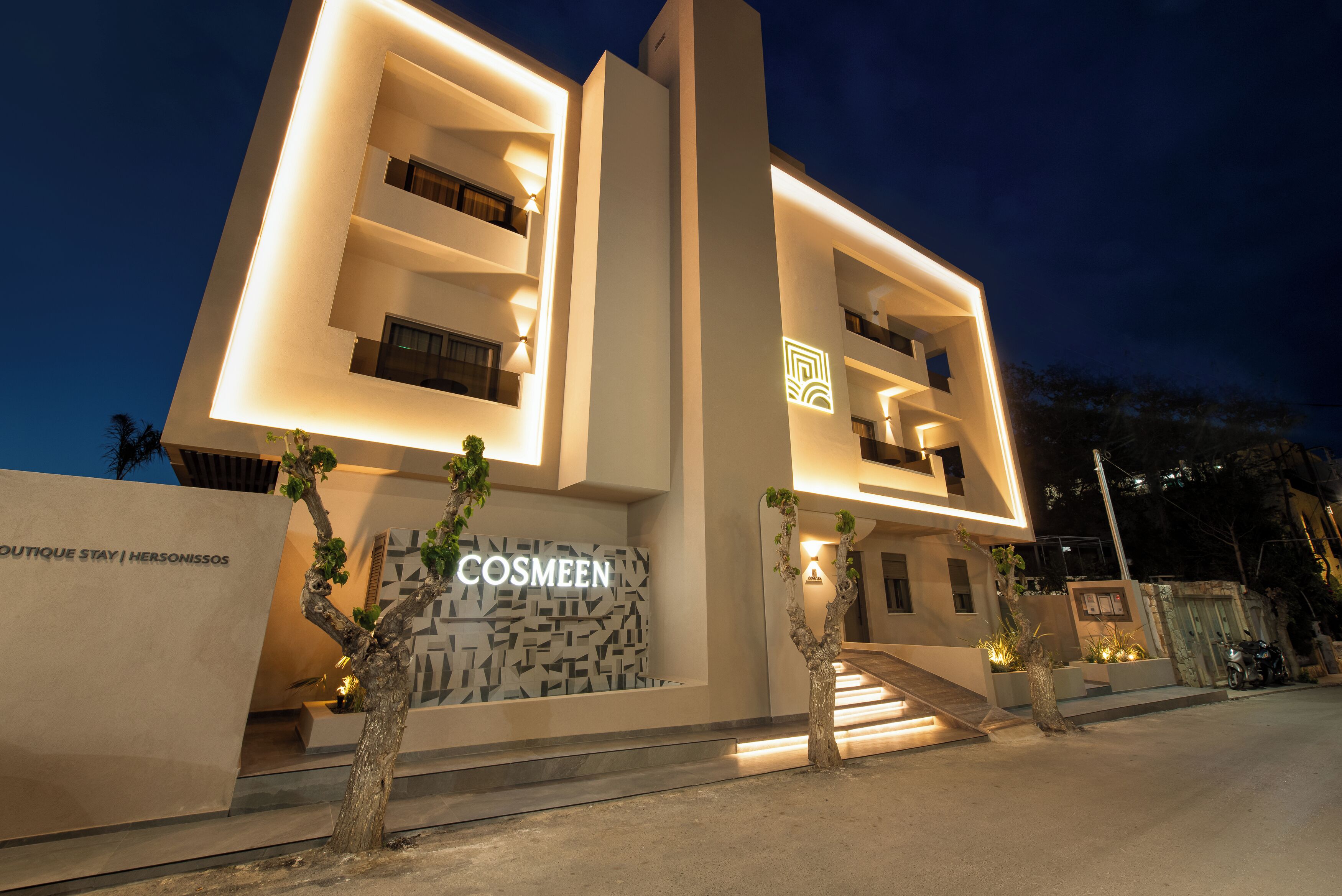 Un hotel moderno con fachada geométrica, entrada visible y un letrero que dice "COSMEEN".