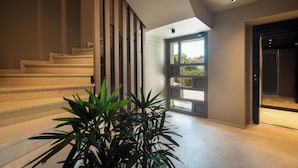 A modern staircase with wooden railings and a potted plant at the bottom.