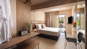 A modern hotel room with a large bed, a desk, a chair, a TV, and a balcony with a view.