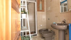 A bathroom with a shower, toilet, bidet, sink, and a wooden cabinet. - [Sunrise] Seaview apartment with large terrace (Orosei)