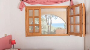 A bedroom with a large window, a bed, a nightstand, and a red lamp. - [Sunrise] Seaview apartment with large terrace (Orosei)