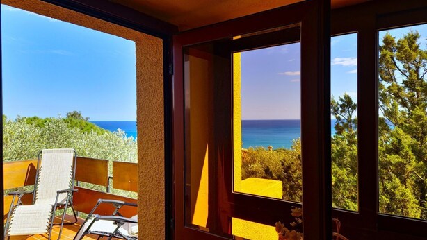 Un balcón con vista al mar y a los árboles.