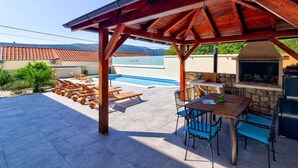 A covered outdoor area with a pool, barbecue grill, and seating.