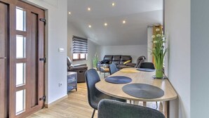 Un comedor moderno con una mesa de madera, sillas negras y un jarrón con flores.
