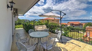 Un balcón con mesa y sillas, una lámpara y vistas al mar y edificios.