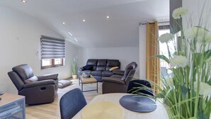 Una sala moderna con un sofá de cuero, un sillón reclinable, una mesa de centro y una mesa de comedor.