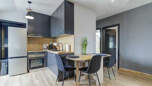 Una cocina moderna con armarios oscuros, encimera de madera y zona de comedor con una mesa redonda y sillas.