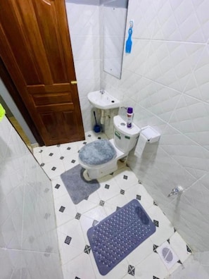 A small bathroom with a toilet, sink, and a mirror.