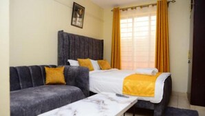 Een kamer met een bed, een bank, een tafeltje en een raam met gordijnen.