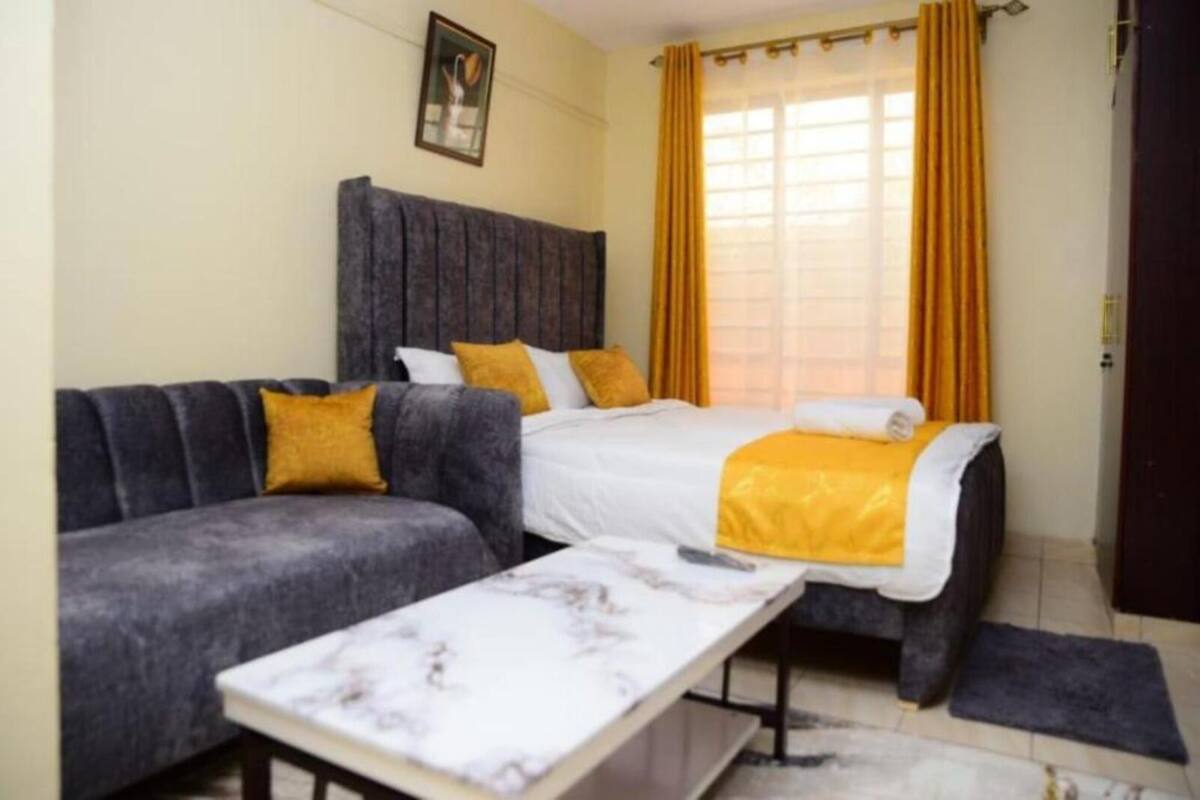 A room with a bed, a sofa, a small table, and a window with curtains.