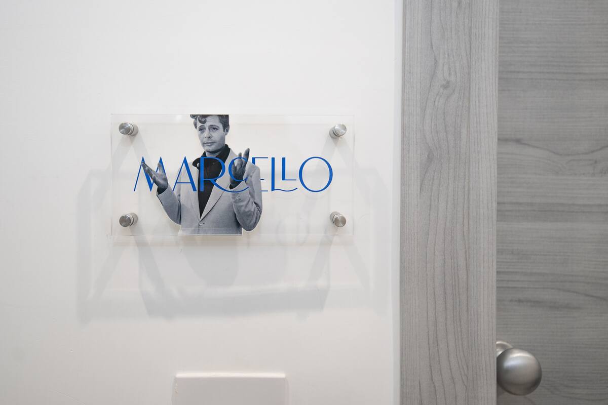 A wall-mounted sign with the name "MARCOLO" and a photo of a person.