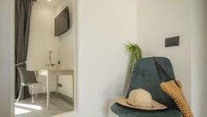 A modern room with a teal chair, a hat, and a plant. - LA DOLCE VITA ROOMS (Procida)