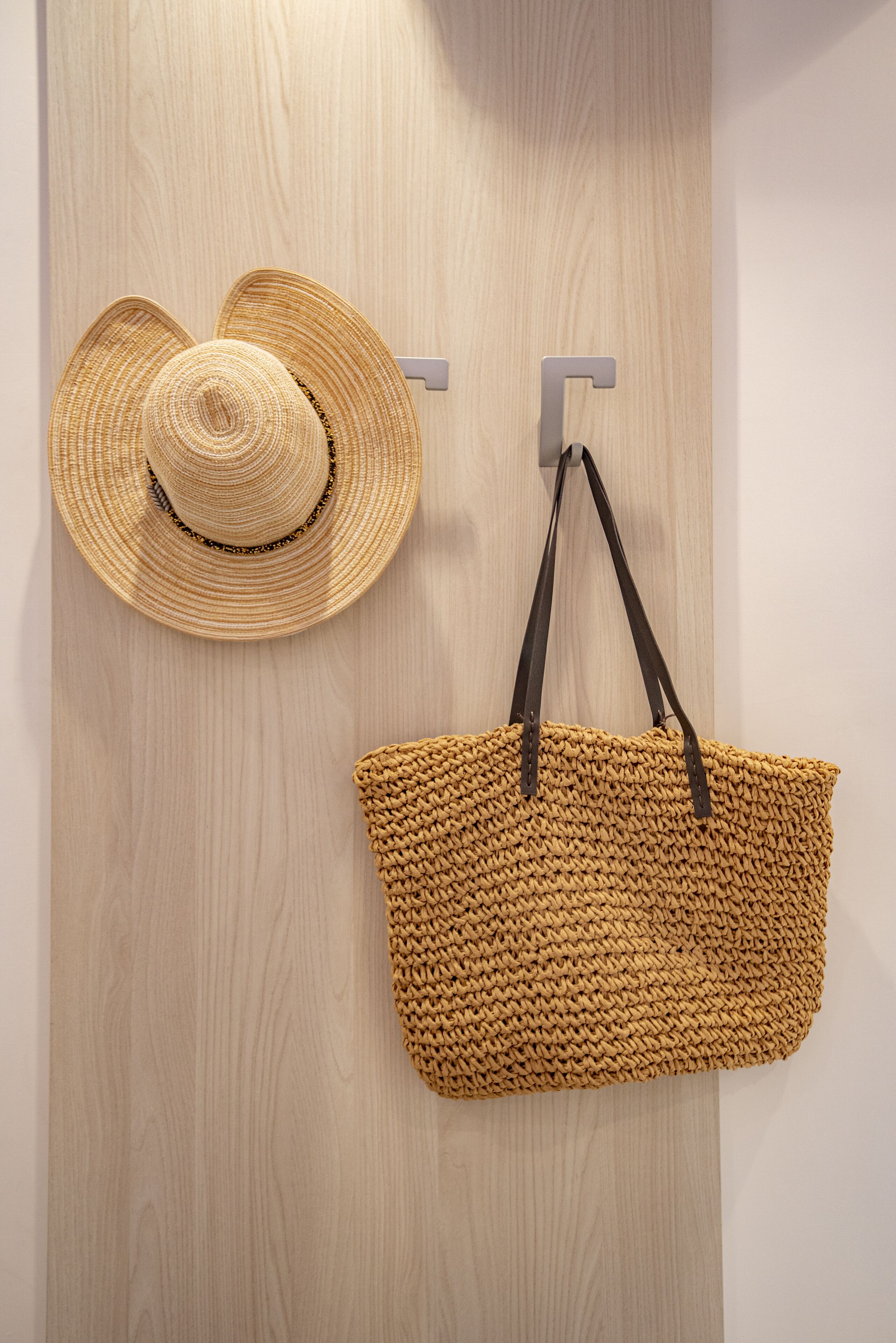 Un chapeau de paille et un sac en tissu tressé sont accrochés à un mur en bois.