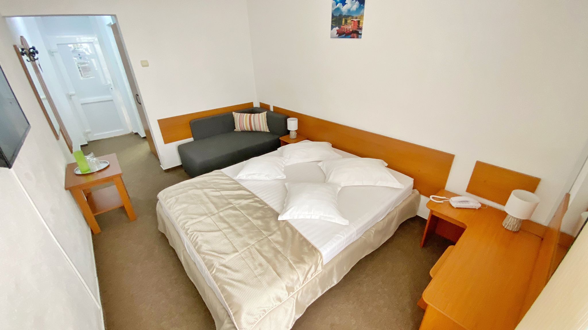 A hotel room with a bed, a bedside table, a nightstand, a chair, and a door.