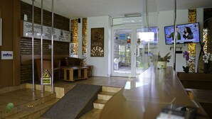 A hotel reception area with a reception desk, seating area, and a staircase leading to the upper floor. - Hotel Decebal Neptun (Neptun)