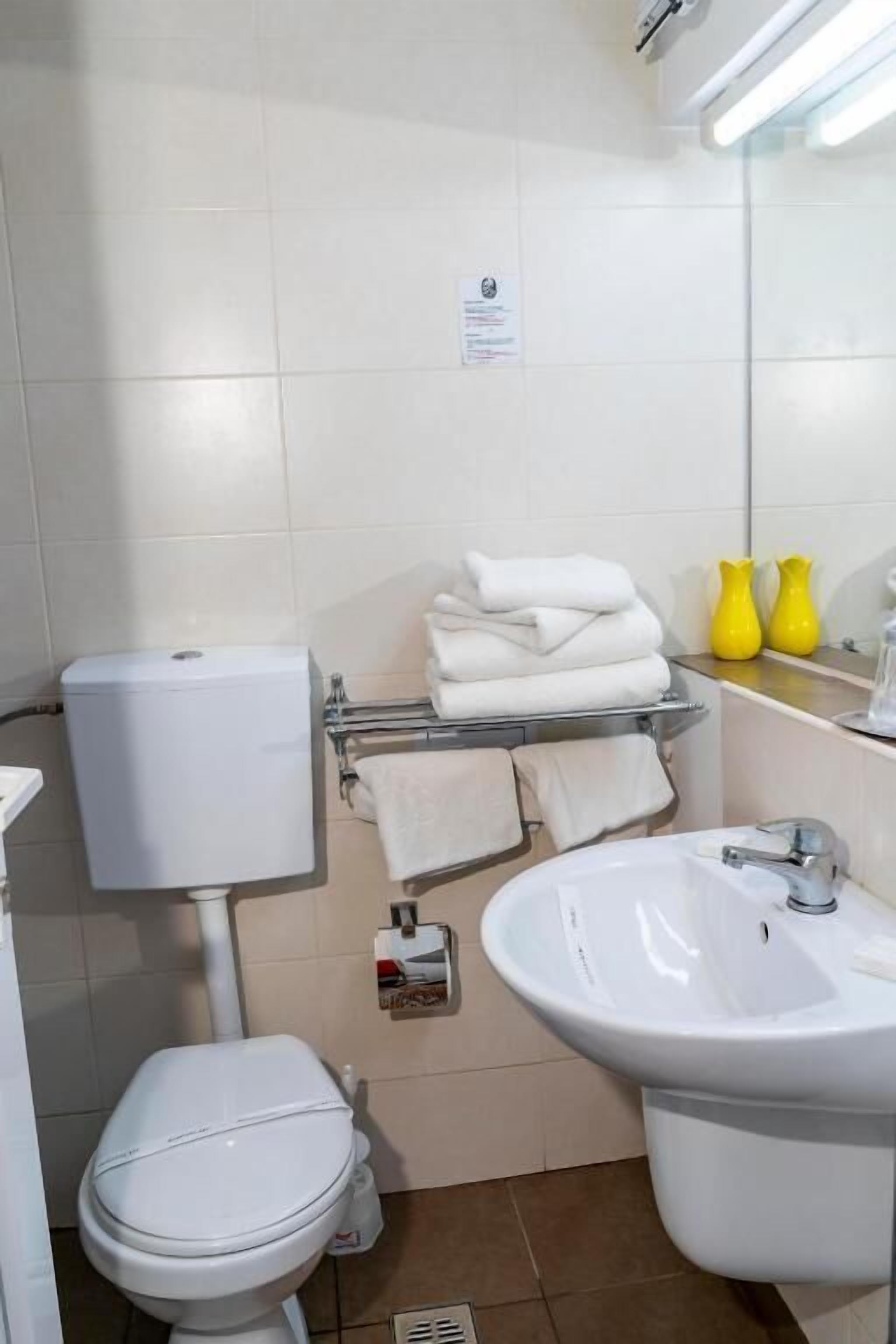 Une petite salle de bain propre, équipée de toilettes, d’un lavabo et d’un porte-serviettes.
