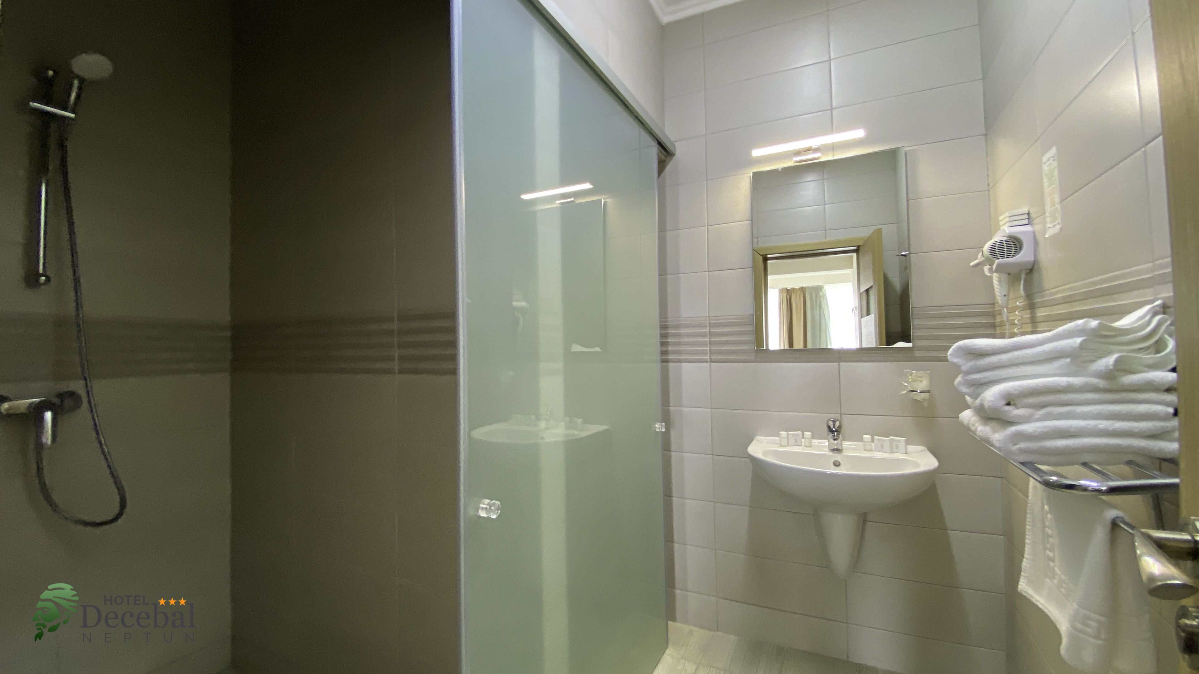 A modern bathroom with a glass-enclosed shower, a sink with toiletries, and a towel rack.
