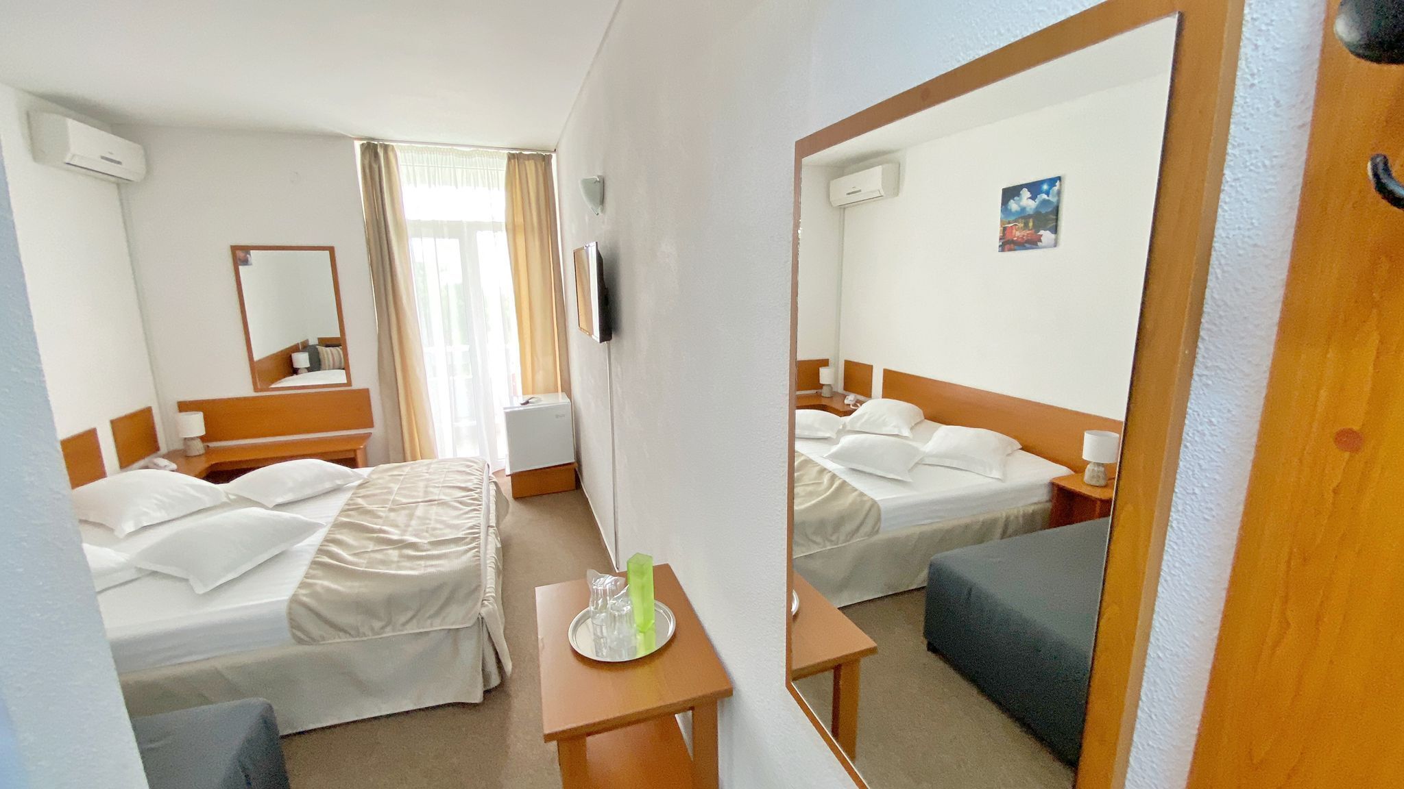 A hotel room with two beds, a desk, a chair, and a mirror.
